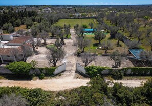 An aerial view of a residential area with a gated entrance, a green field, and surrounding trees. - 3345 DCB Trilocale by Barbarhouse (Melendugno)