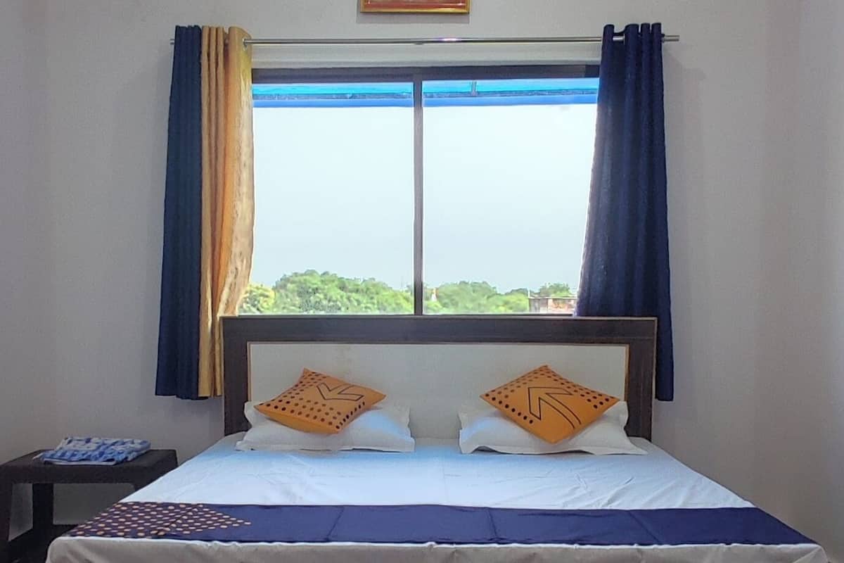Un dormitorio con una cama, una ventana con cortinas, una mesita de noche y un cuadro en la pared.