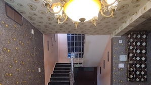 Un vestíbulo con candelabro, paredes con diseño, una escalera y sofás de cuero.