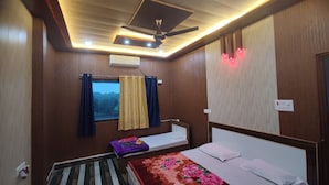 Una habitación con cama, ventana con cortinas, ventilador de techo y aire acondicionado.