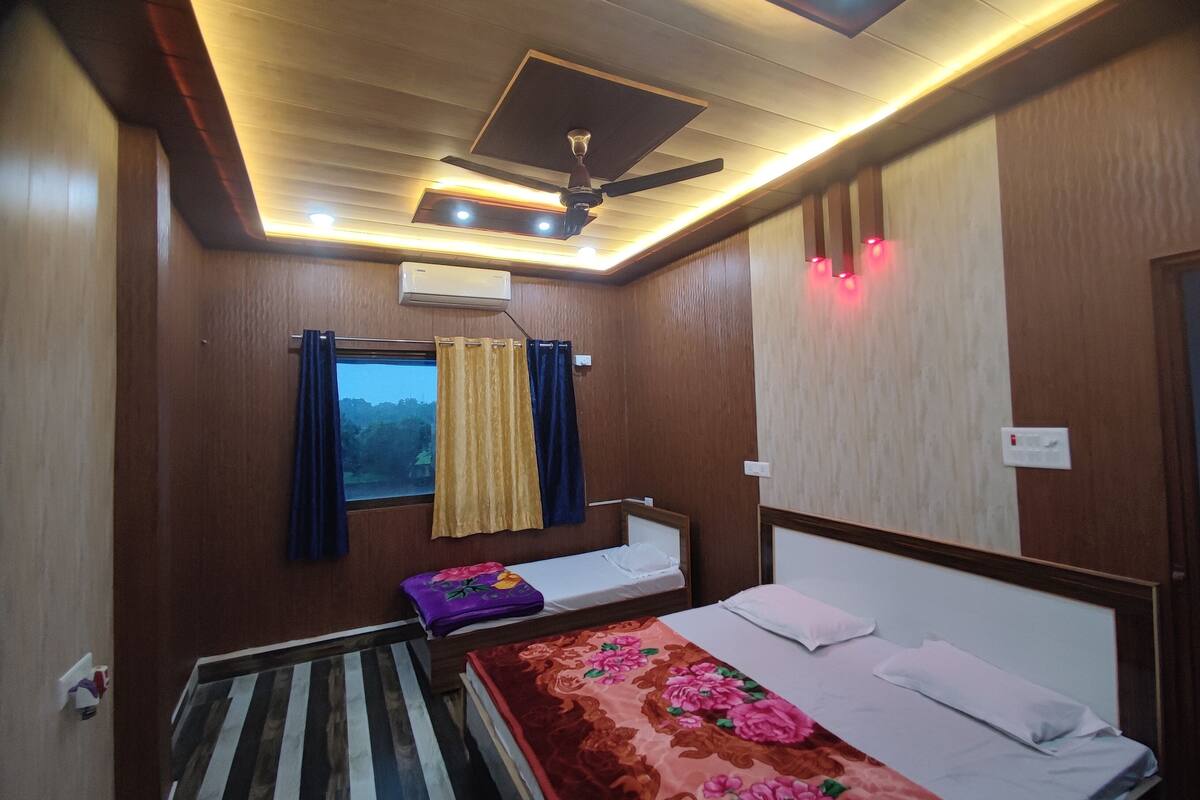 Una habitación con cama, ventana con cortinas, ventilador de techo y aire acondicionado.