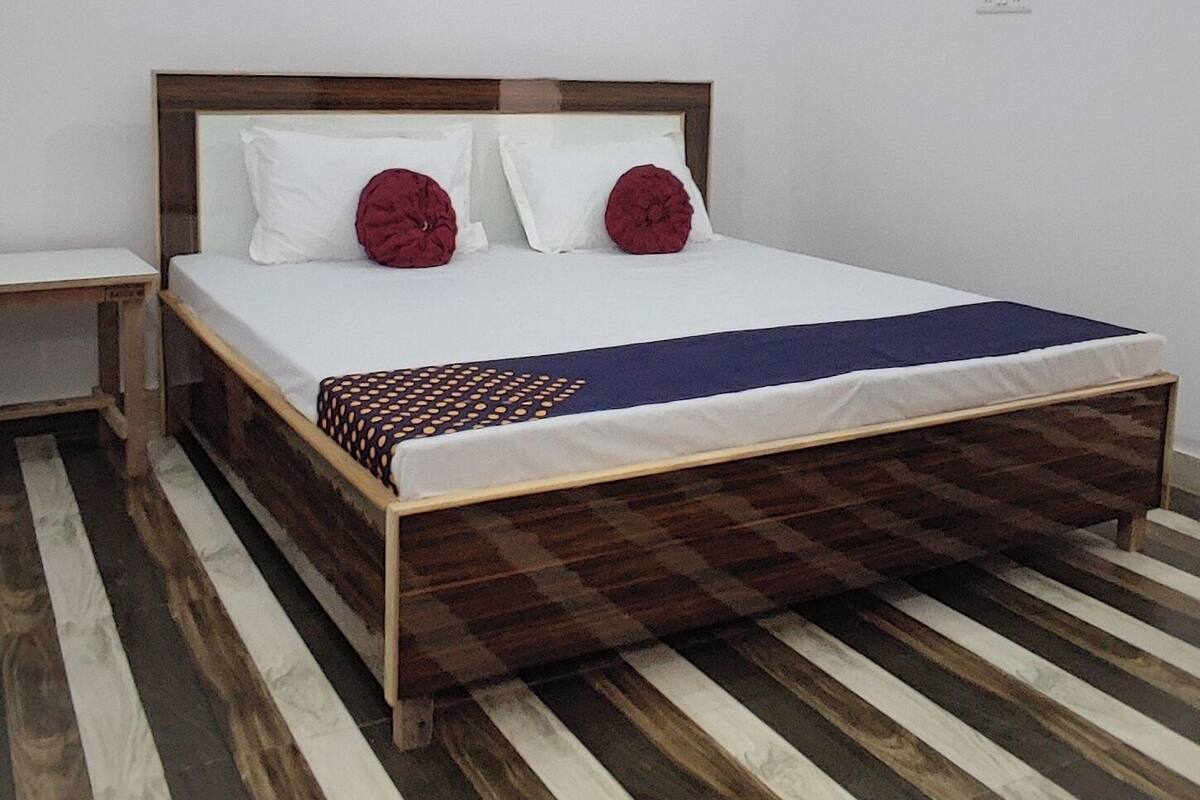 Un dormitorio con cama de madera, paredes blancas, ventilador de techo y un cuadro en la pared.