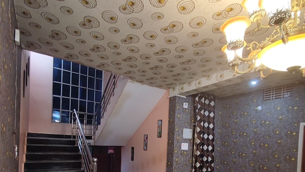 Una sala de estar con una escalera, sofás de cuero, un tapete estampado y una araña.