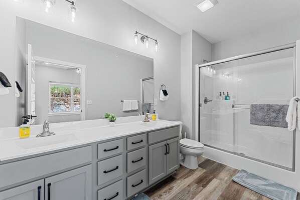 A modern bathroom with a large mirror, a shower, and a toilet.