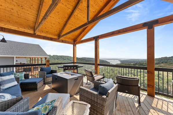 Una terrazza riparata con mobili da esterno, un barbecue e vista sulla valle.