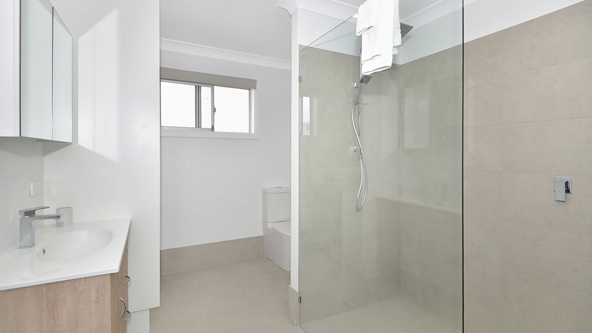 Un baño moderno con cabina de ducha de vidrio, inodoro y lavabo con espejo superior.