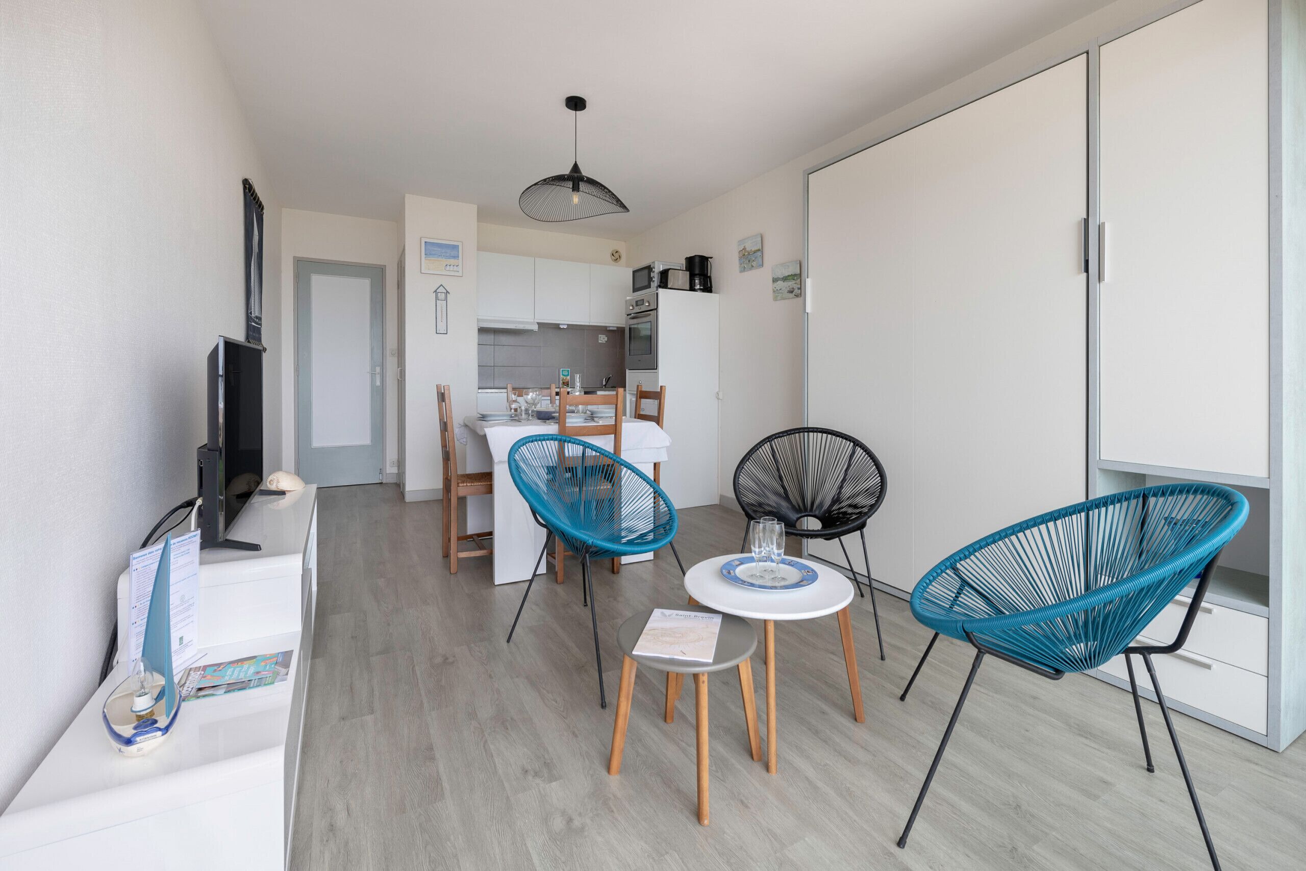 Een knus woongedeelte met een kitchenette, een eethoek met twee stoelen, een kleine tafel en een televisie op een dressoir.