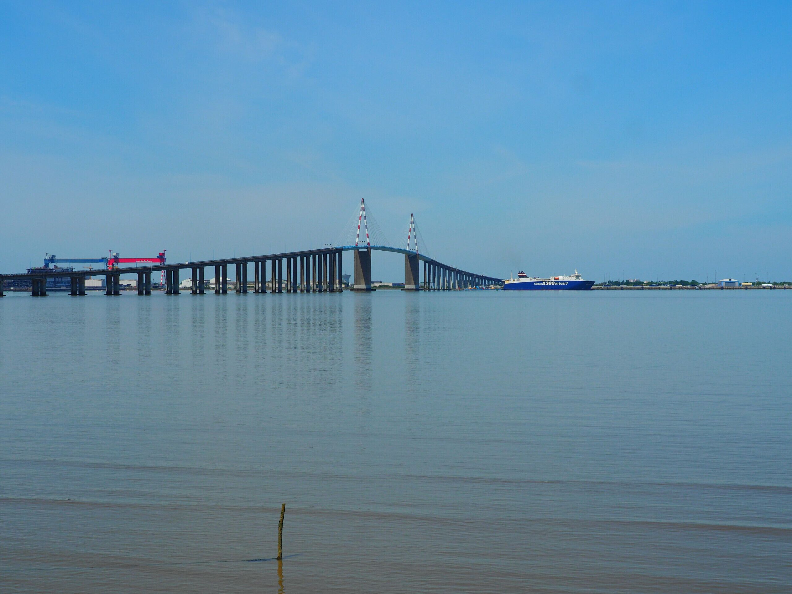 Eine lange Brücke über ruhigem Wasser, ein Schiff in der Ferne.