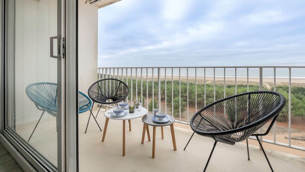 Un balcone con una porta vetrata, due tavoli rotondi e quattro sedie.