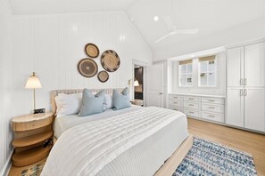 A bedroom with a bed, bedside tables, a ceiling fan, and a wardrobe. - Seaside Siesta a luxury beachfront home steps away from the southern coast (Port Aransas)