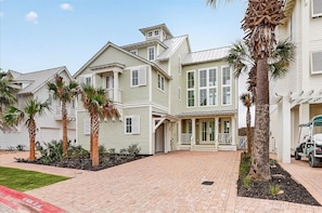 A residential building with a paved driveway, palm trees, and a golf cart. - Seaside Siesta a luxury beachfront home steps away from the southern coast (Port Aransas)