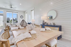 Un coin repas avec une table en bois dressée pour six personnes, entourée de chaises en osier.