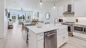 A modern kitchen with white cabinetry, stainless steel appliances, and a central island.