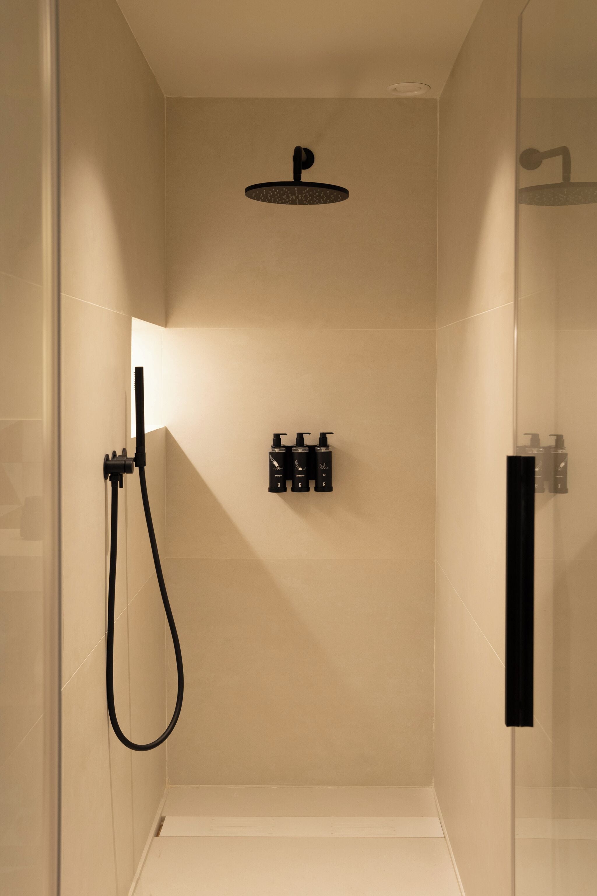 A modern shower with a handheld showerhead and a wall-mounted control panel.