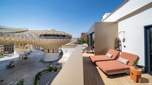 A modern hotel with a unique architectural design, featuring a curved roof structure and a rooftop lounge area with seating and potted plants. - Ocean Drive Sevilla  (Seville)