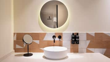 A modern bathroom with a round mirror, a white sink, and a wall-mounted towel rack.