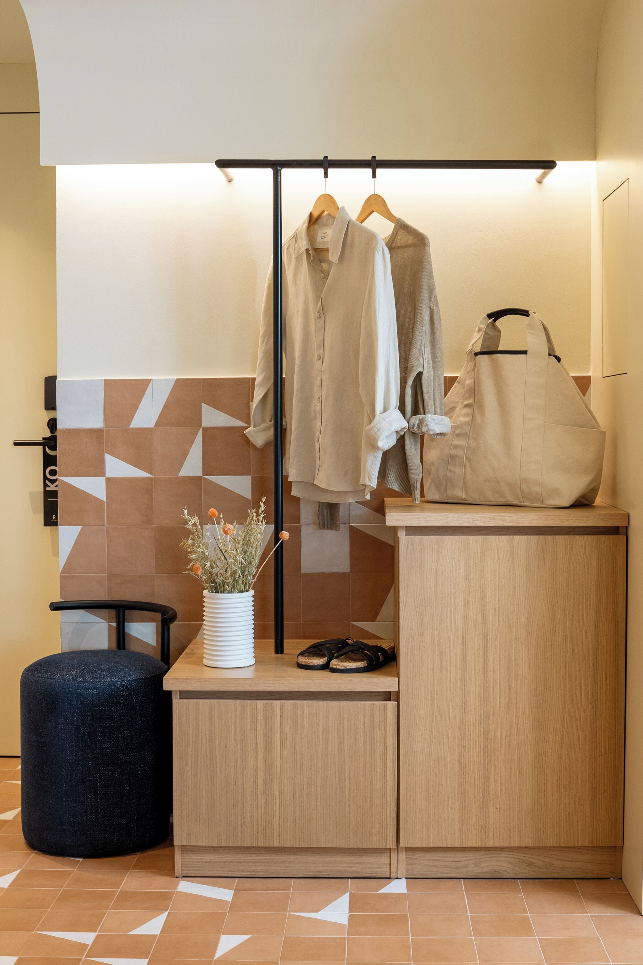 Un baño moderno con un tocador de madera, un perchero y un taburete pequeño.