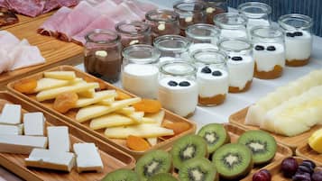 A variety of food items including meats, cheeses, fruits, and desserts on a wooden board.