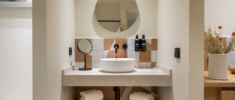 Een moderne badkamer met een ronde spiegel, een rond wastafel en een handdoekhouder.