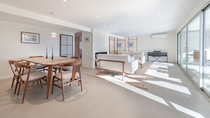A modern interior with a dining area, a sofa, and a large window. - Newly Reno'd GORGEOUS, Water View, Beach Access (CS0034) (Wellfleet)