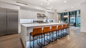 A modern kitchen with a large island, stainless steel appliances, and a seating area with bar stools.