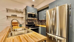 A modern kitchen with stainless steel appliances, a wooden countertop, and a built-in oven. - Updated tree top cabin retreat! (Mammoth Lakes)