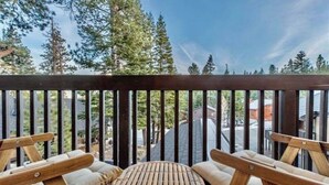 A wooden deck with two wicker chairs and a small round table, surrounded by tall trees. - Updated tree top cabin retreat! (Mammoth Lakes)