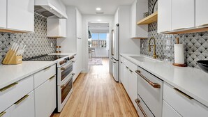 Une cuisine moderne avec des meubles blancs, un îlot central et une vue sur la salle à manger.