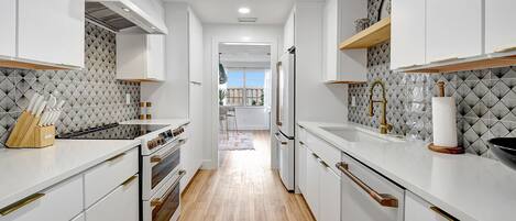 A modern kitchen with white cabinetry, a central island, and a view to the dining area.