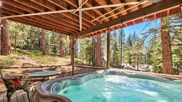 Un jacuzzi bajo una pérgola de madera con vista al bosque.