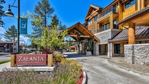L’entrée d’un complexe hôtelier, avec une enseigne indiquant « Zalanta Resort at the Village », se caractérise par une allée couverte et une architecture en pierre et en bois.