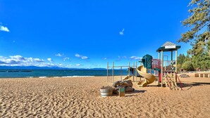 Une plage dotée d’une aire de jeux, comprenant un toboggan et des structures d’escalade, ainsi qu’un petit pavillon.