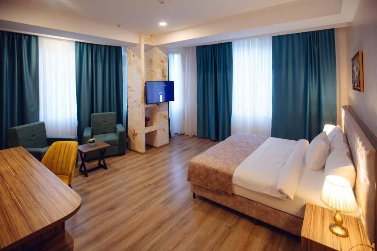 A hotel room with a bed, a desk, a chair, a TV, and a small table.