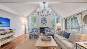 A spacious living room with a large TV, a fireplace, and a high ceiling with skylights. - Walk in minutes to Kiawah's famous beach! (Kiawah Island)