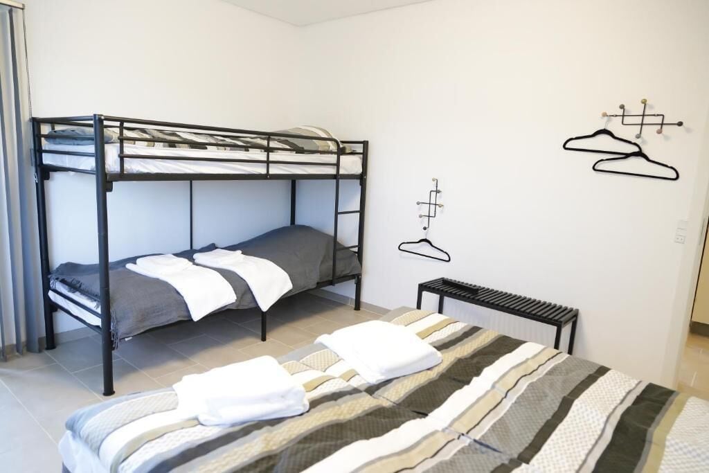 A bunk bed room with a radiator, a small table, and wall-mounted hangers.