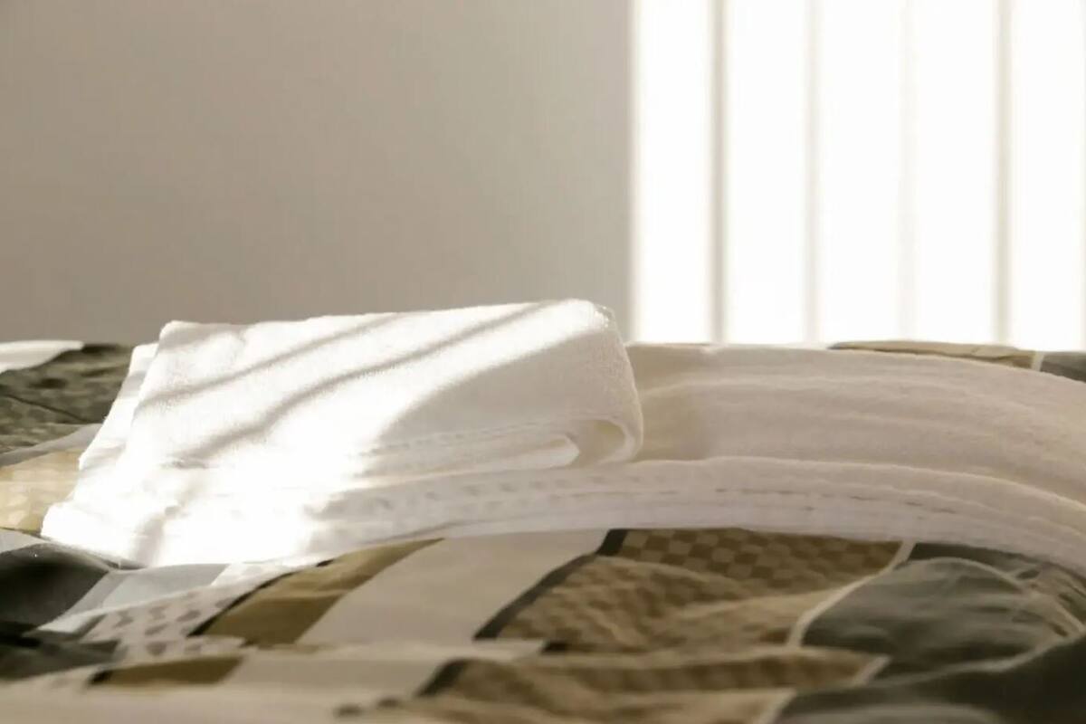 A bed with a patterned bedspread and a white pillow.