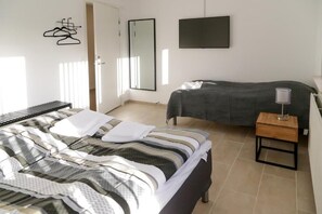 A bedroom with a large bed, a smaller bed, a TV, and a bedside table. - Hotel Ikast (Ikast)