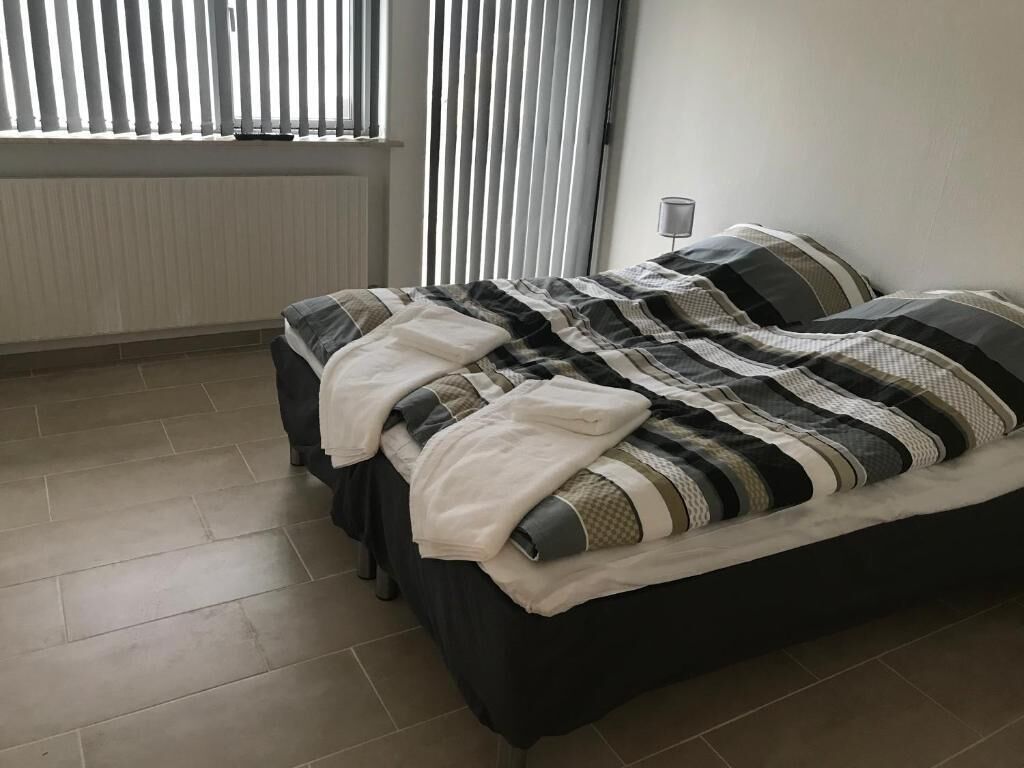 Una camera da letto con un letto, un termosifone e una finestra con tende.
