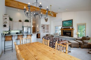 A spacious kitchen with a wooden dining table, bar stools, and a chandelier. - Mountainscape Long Stay Townhome: 30+ Day Rental w/ Breathtaking Views (Breckenridge)