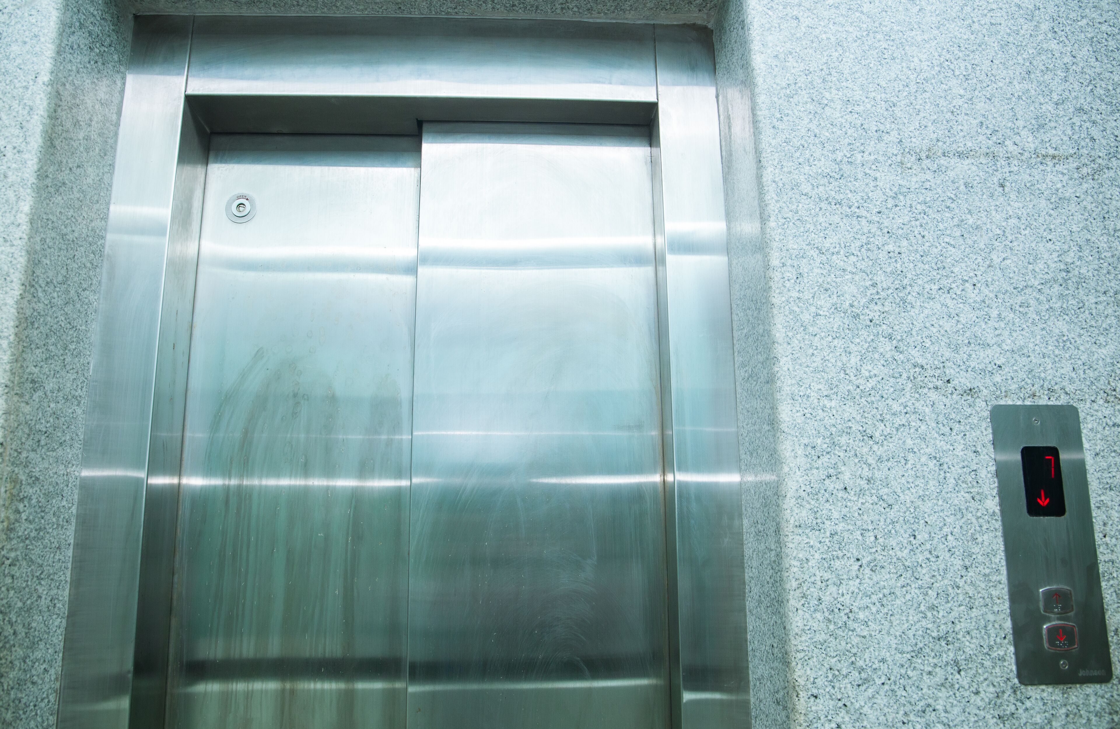 A metallic elevator door with a control panel on the right.