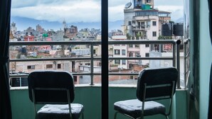 A room with two chairs facing a large window overlooking a cityscape with buildings and mountains. - Yaksa Hotel Pvt. Ltd. (Kathmandu)