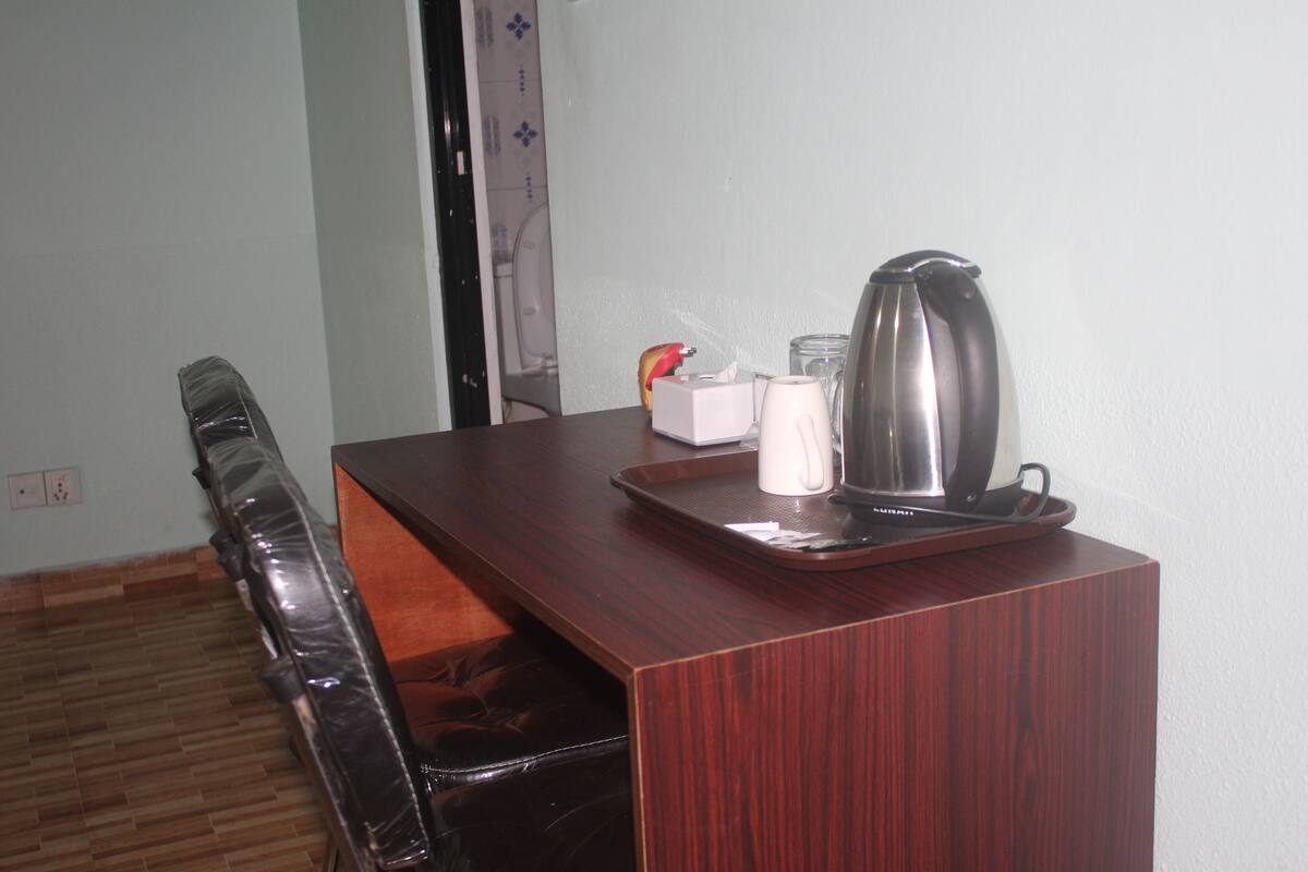 Una mesa de madera con una bandeja, una taza blanca y un hervidor de acero inoxidable.