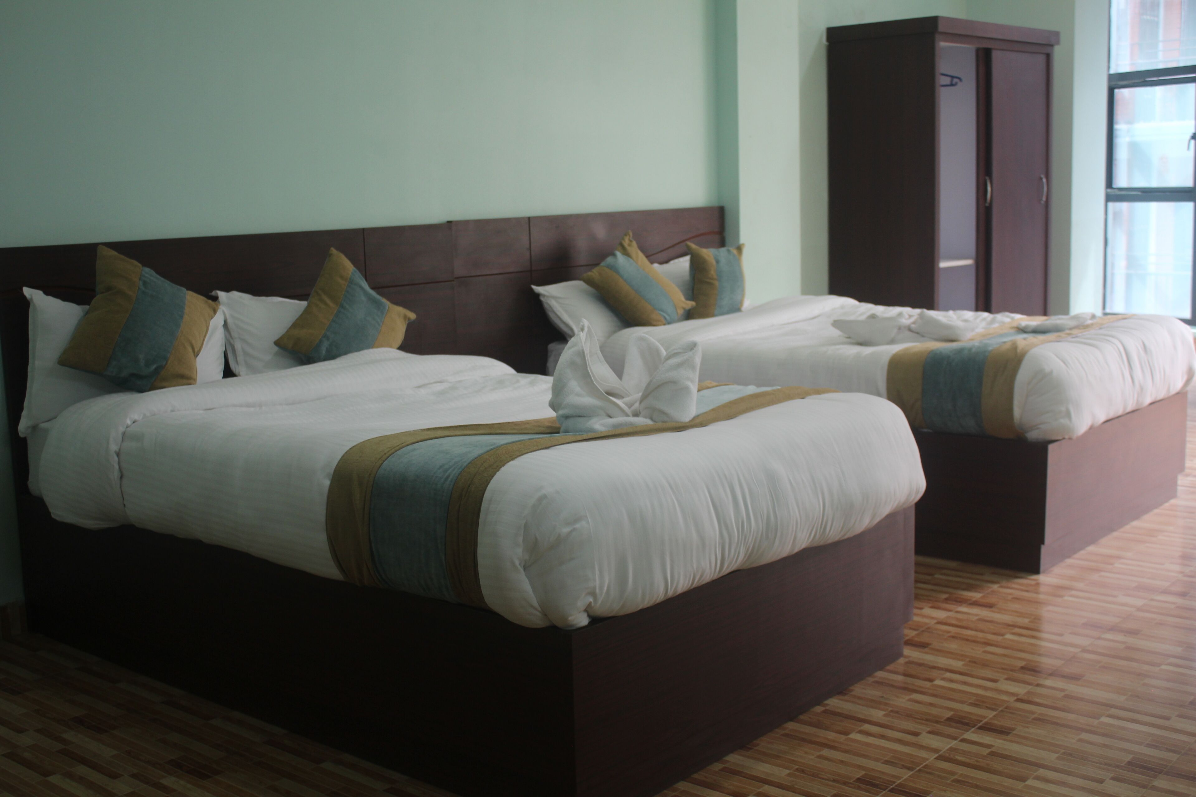 A hotel room with two beds, a wardrobe, and a large window.
