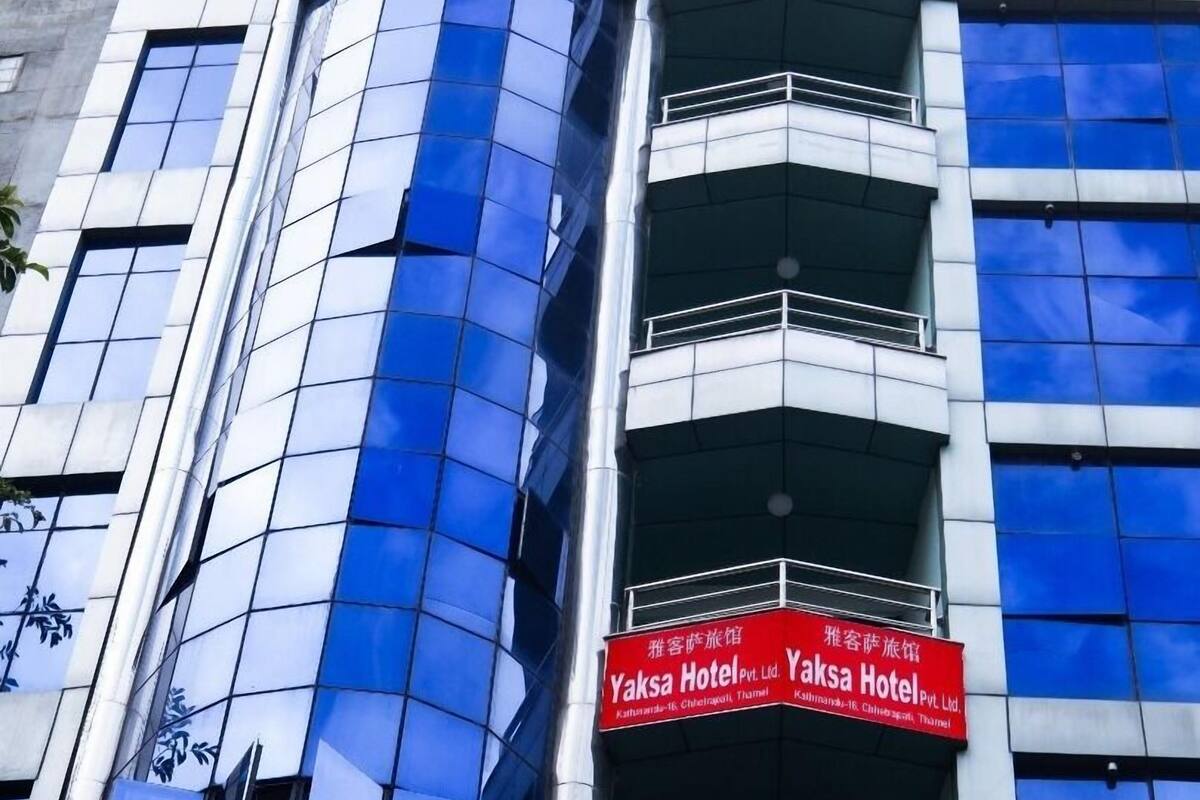 Un edificio moderno con fachada de vidrio curva y un letrero rojo que indica que es el Hotel Yaksa.