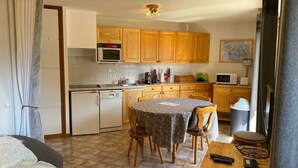 A compact kitchen with wooden cabinets, a microwave, a sink, and a dining area with a table and chairs.
