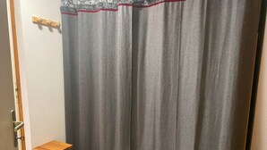 A room with a grey curtain, a wooden stool, and a door with a handle.