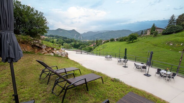 An outdoor patio with lounge chairs and tables, overlooking a mountainous landscape. - Apartamentos Las Caldas . Castillo de Priorio , 15 Minutos del Centro de Oviedo (Priorio)
