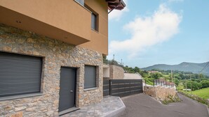 A modern two-story building with stone facade and a garage door. - Apartamentos Las Caldas . Castillo de Priorio , 15 Minutos del Centro de Oviedo (Priorio)