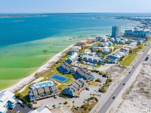 An aerial view of a coastal resort with beachfront properties, a pier, and a large hotel complex.