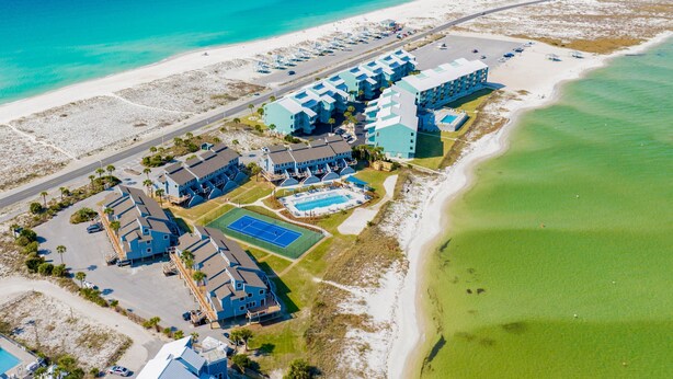 Vista aérea de un hotel costero con varias construcciones, una piscina y una playa.
